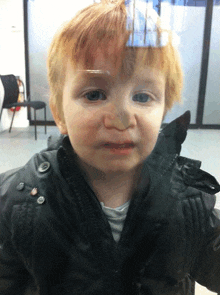 a little boy with red hair is looking through a window