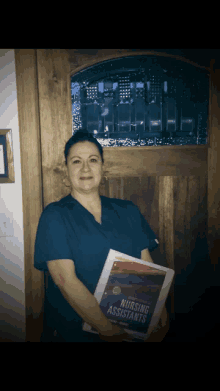 a woman holding a book that says nursing assistants on it