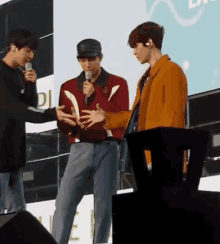 a group of young men are standing next to each other on a stage holding microphones .