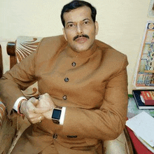 a man in a suit is sitting in a chair with his hands folded .