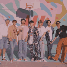 a group of young men are standing in front of a wall with a basketball hoop