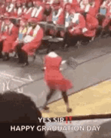 a girl in a red dress is dancing in front of a crowd of people at a graduation ceremony .