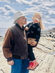 a man in a hat holds a little girl in a leopard print outfit