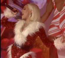 a woman is singing into a microphone while wearing a santa claus outfit