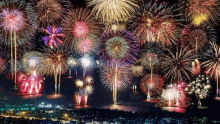 a bunch of fireworks are flying over a city at night .