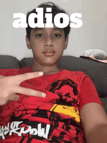 a boy wearing a red shirt with the word adios on his face