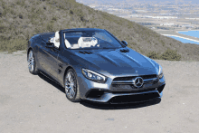 a mercedes convertible is parked on the side of a dirt road