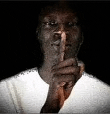 a man is holding his finger to his mouth in a dark room .