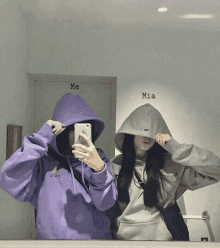 two girls wearing hoodies are taking a picture of themselves