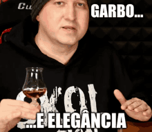 a man wearing a garbo shirt holds a glass of whiskey