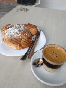 a croissant on a plate next to a cup of coffee on a table