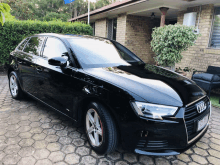 a black audi is parked in front of a house