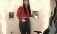 a woman in a red top and black pants is standing in a room .