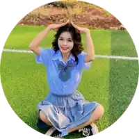 a girl in a blue shirt and skirt is kneeling on the grass