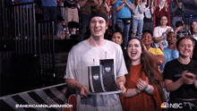 a man is holding a trophy in front of a crowd and the nbc logo can be seen in the background