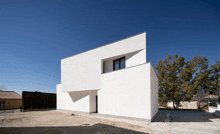 a white building with a black window and a blue sky in the background