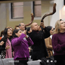 a man blowing a shofar horn in front of a crowd at iglesia de cristo esenezer chicago