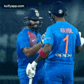 two cricket players , rahul and virat kohli , are shaking hands on a field .