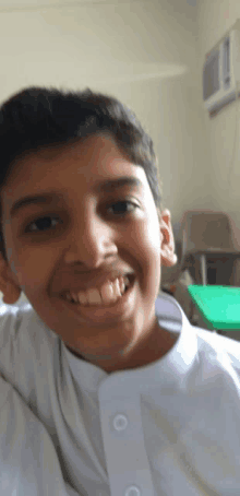 a young boy wearing a white shirt is smiling