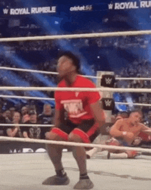 a man in a red shirt is kneeling in a boxing ring .