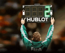 a man is holding up a sign that says hublot .