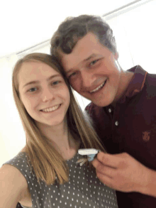 a man and a woman posing for a picture with the man wearing a maroon polo shirt