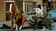 a man sitting on a pile of garbage next to a horse wearing a kimba beanie