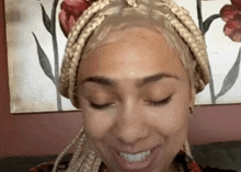 a woman with braids in her hair is smiling with her eyes closed .