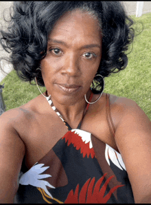 a woman taking a selfie wearing a floral top and hoop earrings