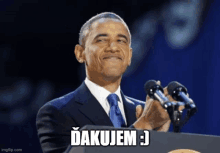 barack obama is giving a speech in front of two microphones with a caption that says " dakujem "