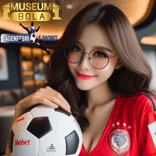 a woman wearing glasses holds a soccer ball in front of a museum bola logo