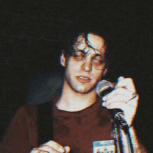 a man singing into a microphone with a badge on his shirt that says ' i love you '