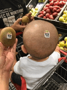 a baby is sitting in a shopping cart with a kiwi on his head