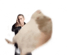 eminem is holding a hamster in front of him and pointing at it .