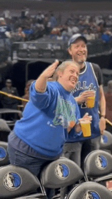 a woman in a dallas jersey is sitting in the stands with a man