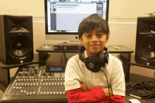 a boy wearing headphones stands in front of a computer