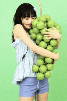 a girl is holding a bunch of green apples in her arms