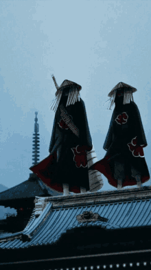 a couple of people standing on top of a building with a cloud symbol on their outfits