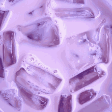 a close up of a purple drink with ice cubes and milk .