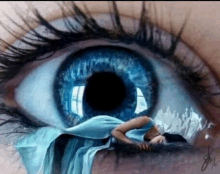 a woman in a blue dress is laying down in front of a blue eye .