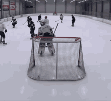 a hockey game is being played on a rink and the goalie is wearing a jersey that says ' american ' on it