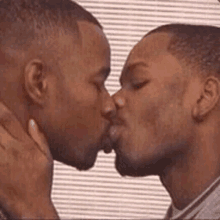 two men are kissing in front of a window .