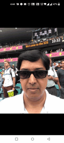 a man wearing sunglasses stands in front of a welcome to the scg sign