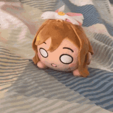 a stuffed toy of a girl with a bow on her head is laying on a bed