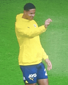 a soccer player wearing a yellow sweatshirt and blue shorts with avg on them