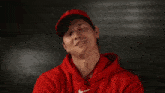 a man wearing a red nike hoodie and a red hat is smiling