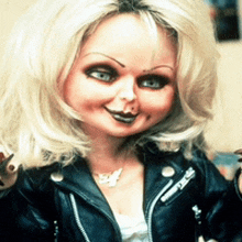 a doll is wearing a black leather jacket and a necklace