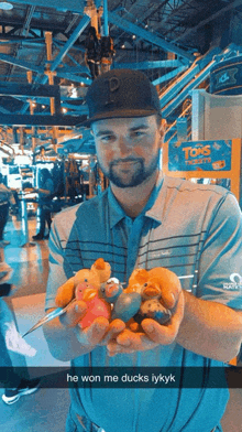 a man holding a bunch of stuffed ducks in front of a sign that says toms