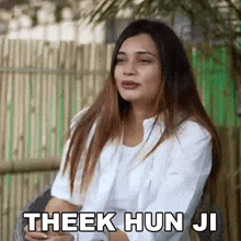 a woman in a white shirt is sitting in a chair with the words theek hun ji written above her .