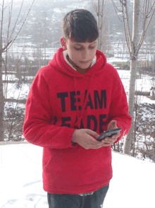 a young man wearing a red team reade hoodie looks at his cell phone